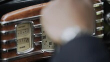 Brown dashboard with speedometer in old retro car. A man in suit puts his hand with wristwatch on the steering wheel.