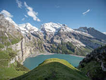 Grass Hill And Alpine Lake In The Alps Of Switzerland.