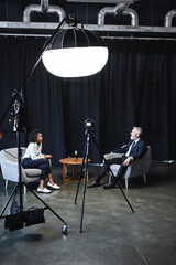 african american journalist talking with businessman in interview studio