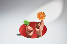 Hands Holding Slices Of Orange And Lime Through Hole