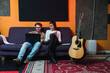 © Kike Arnaiz/Stocksy - Couple sitting on a sofa in music studio.