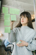 © Mihajlo Ckovric/Stocksy - Young woman writing notes on a stickers on a glass wall