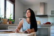 © Eloisa Ramos/Stocksy - Latin woman writing notes in a notebook at kitchen
