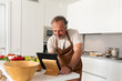 © Valentina Barreto/Stocksy - Senior man watching a tutorial to make a recipe at kitchen