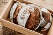 © Jarusha Brown/Stocksy - Woman holds fresh made sourdough bread in a wood crate.