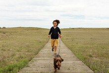 Kid And His Dog Running On The Beach Deck