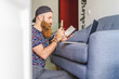 © Alba Vitta/Stocksy - Young bearded man at home working on laptop in couch