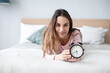 © BestForYou - Pretty woman with an alarm clock in her hands lies on the bed