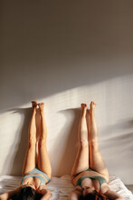 Two Girls Lying On The Bed With Their Legs Up (front View)