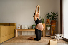 Pregnant woman doing yoga poses at home