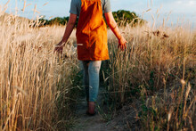 Girl Walking Away Through Field Of Weeds Closer.
