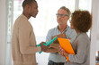 © KOTO - Colleagues talking and smiling in office, holding documents