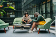 © Luis Velasco/Stocksy - Two Women Sitting On A Couch In A Coworking Workplace.