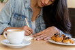 © Alba Vitta/Stocksy - Young woman writing notes while coffe break