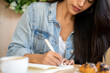 © Alba Vitta/Stocksy - Young woman writing notes while coffe break