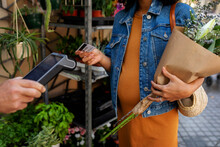 Pregnant Woman Paying With Credit Card At Florist