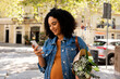 © Valentina Barreto/Stocksy - Pregnant woman with flowers using her phone outdoor