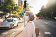 © Santi Nuñez/Stocksy - Side view of mature woman with face mask crossing the street looking away