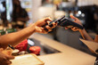 © BONNINSTUDIO/Stocksy - Crop client making contactless payment on POS terminal in cafe