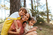 © BONNINSTUDIO/Stocksy - Loving mother with children embracing in countryside woods