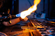 © Albert Martinez/Stocksy - Close-up of the torch flame of a glassblower working with glass tube