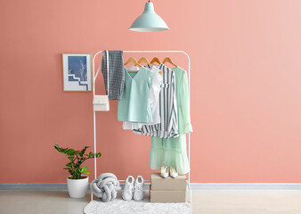 Wall Mural - Rack with stylish clothes and shoes near color wall