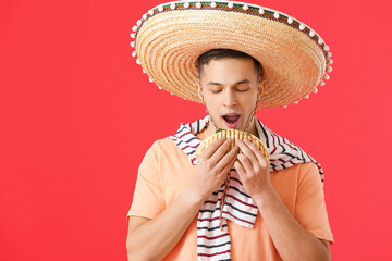 Sticker - Young Mexican man eating tasty quesadilla on color background