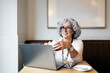 © Santi Nuñez/Stocksy - Mature woman using laptop and drinking coffee in a cafe