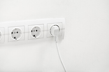 Wall Mural - Electric socket with plug on light wall