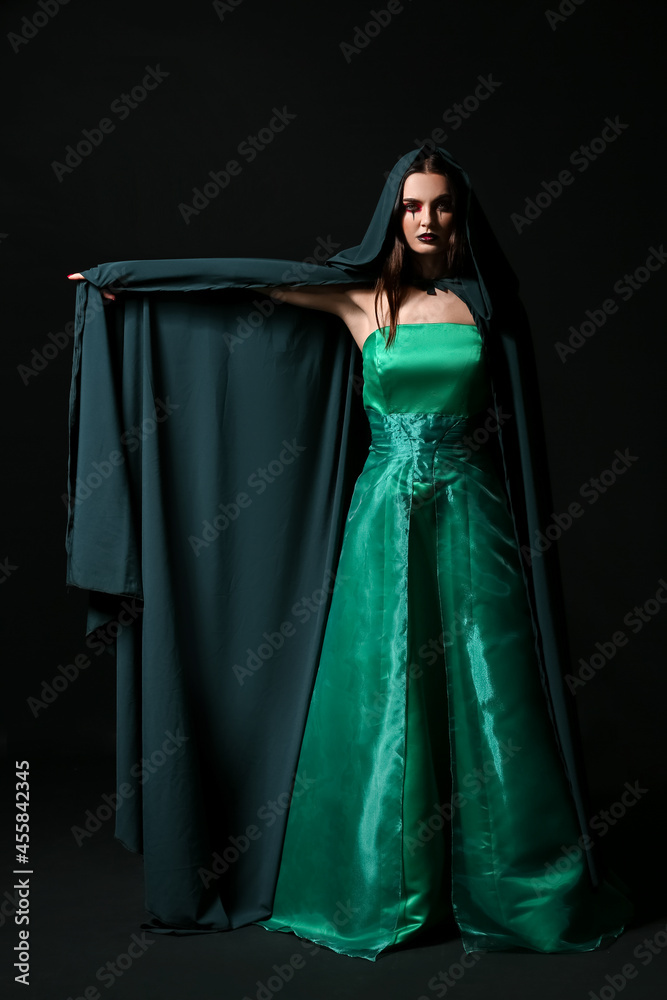 Beautiful woman dressed as witch for Halloween on dark background