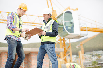 Wall Mural - Construction workers with clipboard talking at construction site