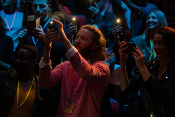 Smiling audience using smart phone flashlights for speaker