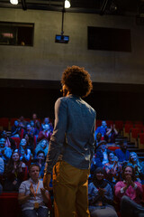 Audience watching male speaker with arms outstretched on stage