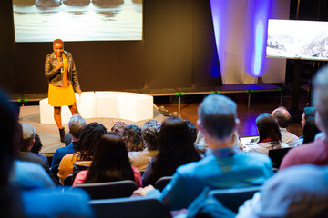 Female speaker on stage talking to audience