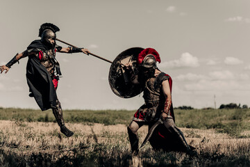 Battle with spear and sword between two ancient warriors in battle dress on meadow.