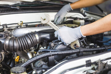 A car mechanic is doing a car repair in a repair shop.