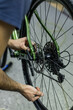 Cropped shot of professional mechanic working in bicycle repair shop, worker repairing bike using special tool