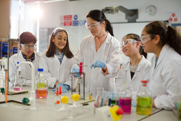 Wall Mural - female teacher and students conducting scientific experiment, watching liquid in test tube in labora