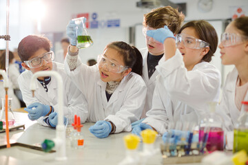 Wall Mural - curious students conducting scientific experiment, examining liquid in beaker in laboratory classroo
