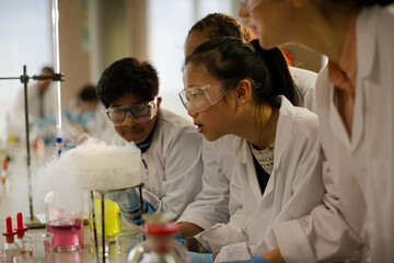 Wall Mural - female teacher and students watching scientific experiment chemical reaction in laboratory classroom