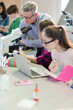 © KOTO - Male teacher and girl students conducting scientific experiment at microscope and laptop in laboratory classroom