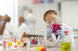 © KOTO - Girl student examining pink liquid, conducting scientific experiment in laboratory classroom