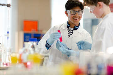 Wall Mural - boy students examining liquid in test tube, conducting scientific experiment in laboratory classroom