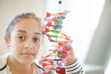 Girl student examining DNA model in classroom