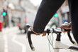 Hands on man on bicycle handlebars, commuting on sunny urban street