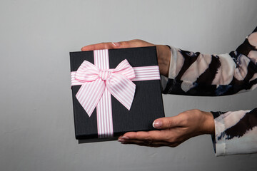 Wrapped gift box in a woman's hands. Christmas, New Year, Birthday or Valentine's Day concept