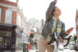 © KOTO - Young woman commuting on bicycle, texting with cell phone on sunny urban street
