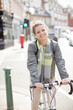© KOTO - Portrait smiling young woman commuting, riding bicycle on sunny urban street