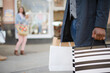 © KOTO - Young man walking along storefront, carrying shopping bags