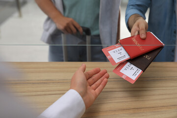 Wall Mural - Man giving passports with tickets to agent at check-in desk in airport, closeup